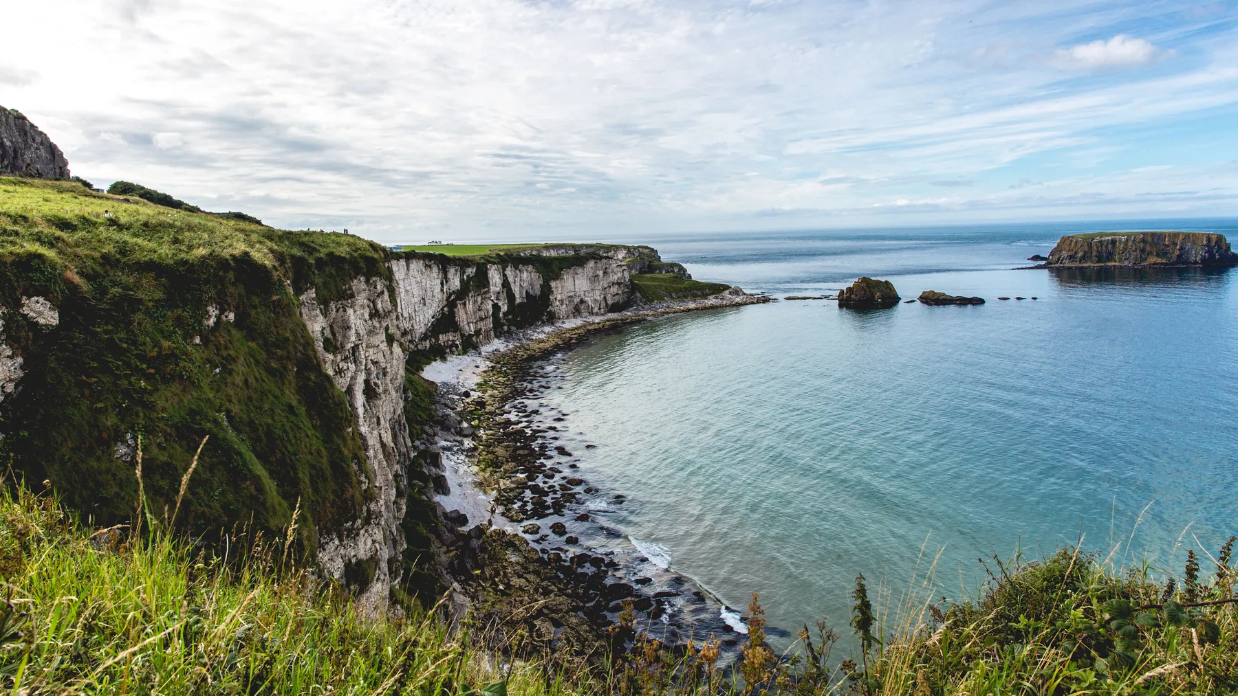 Green clifftops above a sheltered bay on a rocky coast