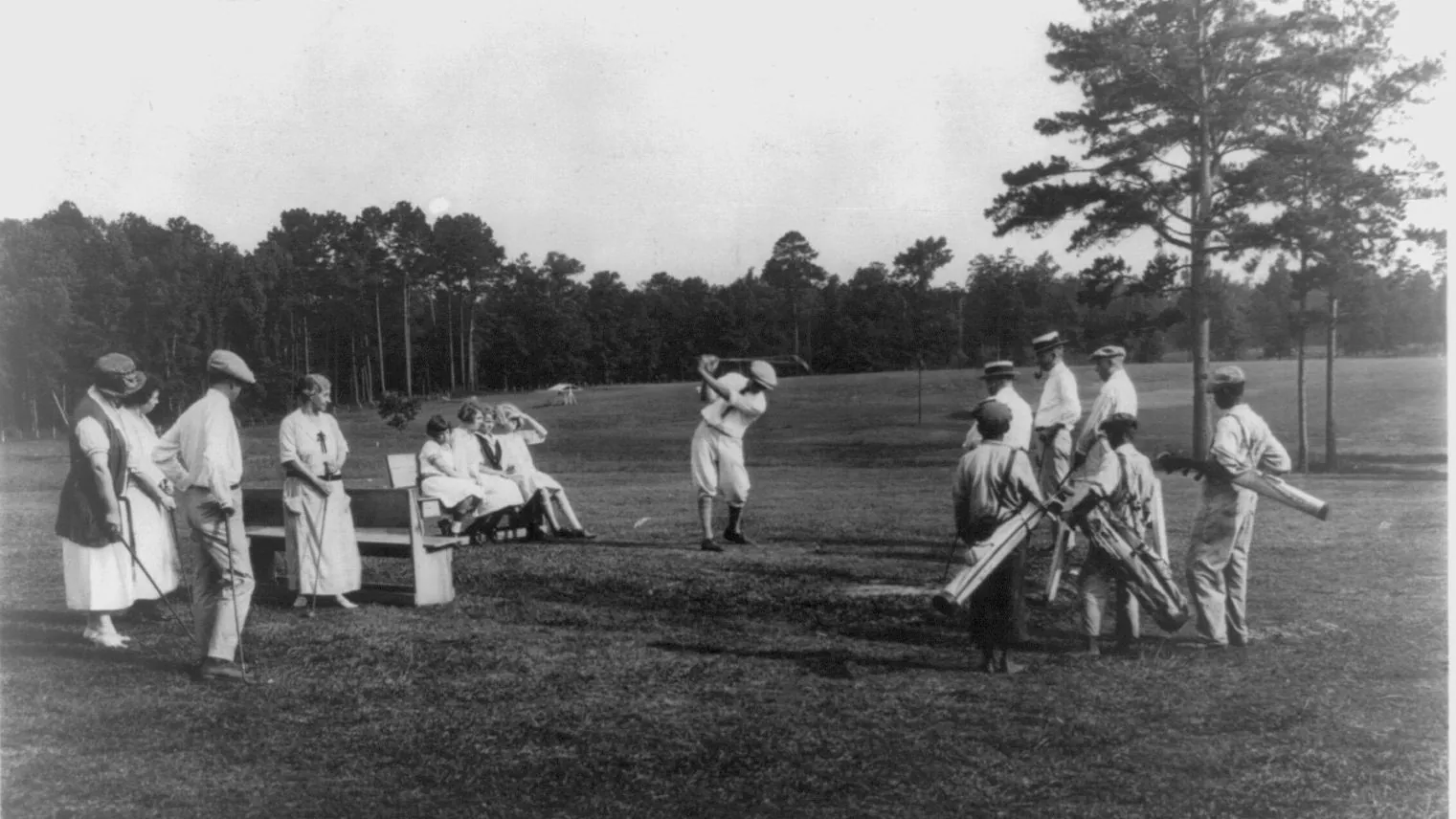 Golfers and caddies around the first tee of an American course in the early twentieth century
