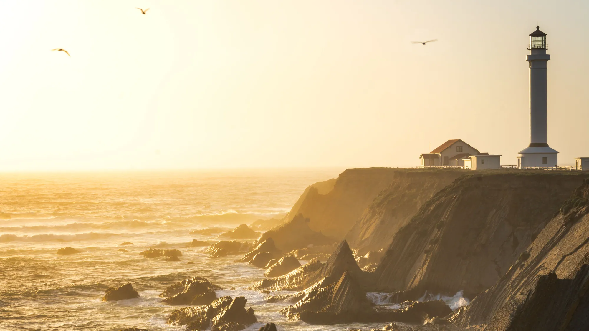 Golden evening light over sea cliffs and a lighthouse